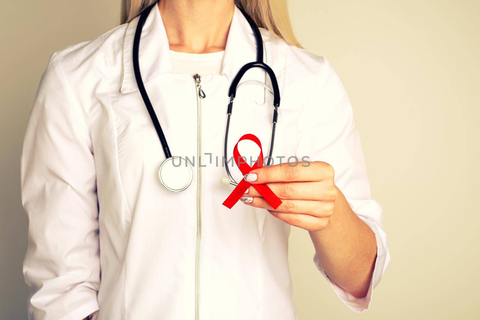 Female doctor withAID, HIV red ribbon. Cancer concept. Doctor Holds Red Ribbon to awareness world aids day Dec. 1. - Image