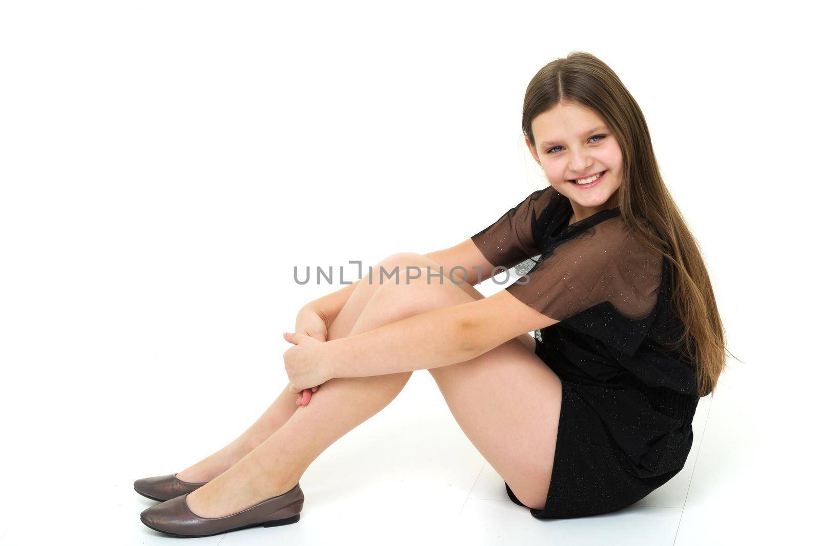 Teen girl teenager sitting on the floor in the studio. The concept of style and fashion. Isolated on white background.