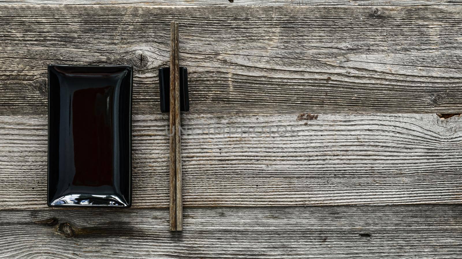 black plate and chopsticks for sushi on wooden background