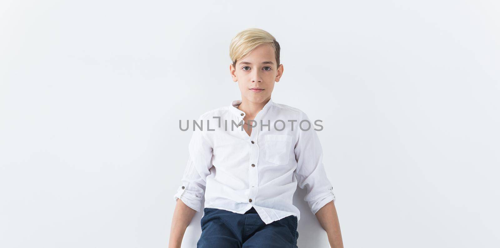 Solitude, loneliness and boredom concept - Bored teen student sitting in a school chair isolated on white background with copy space. by Satura86