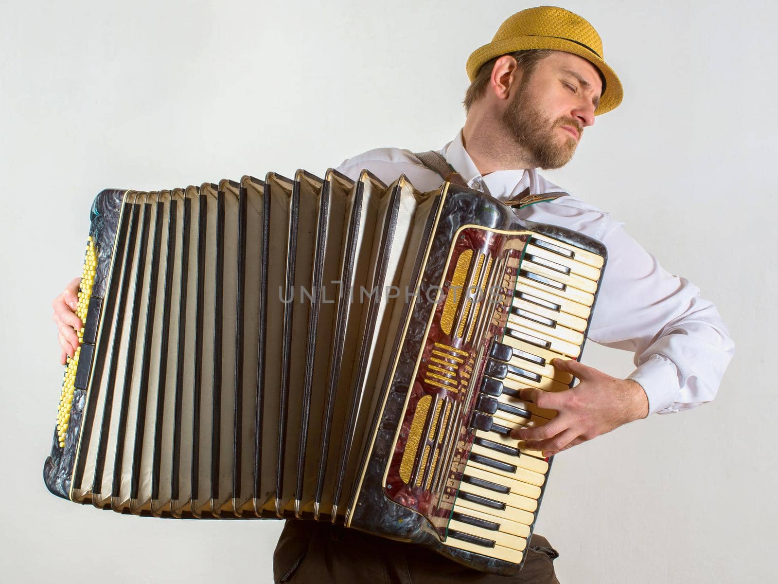 Portrait of a man in straw hat playing on accordion.