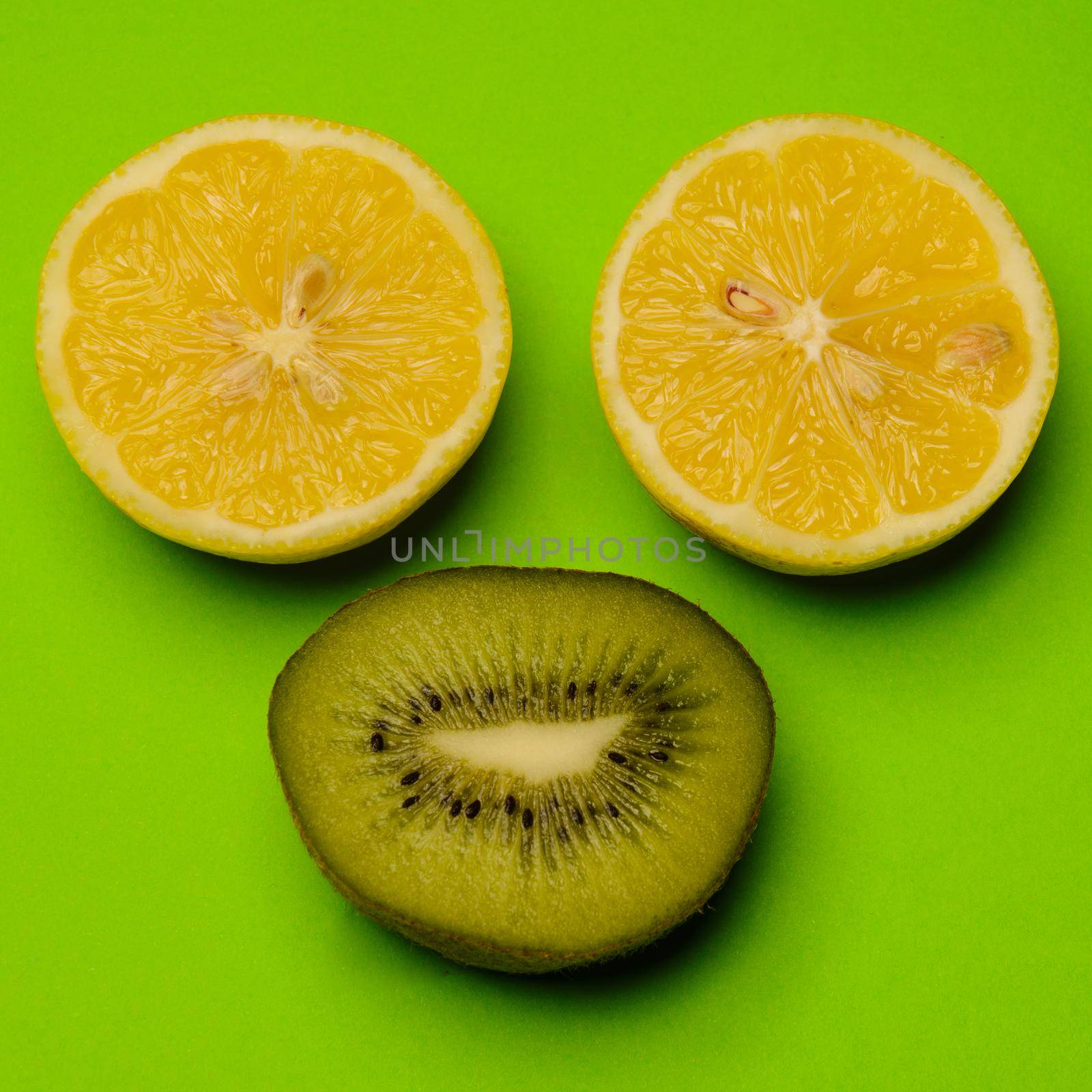 Smiley from the kiwi and lemon on a colored background. Fresh kiwis and lemon fruit, interesting fruit composition