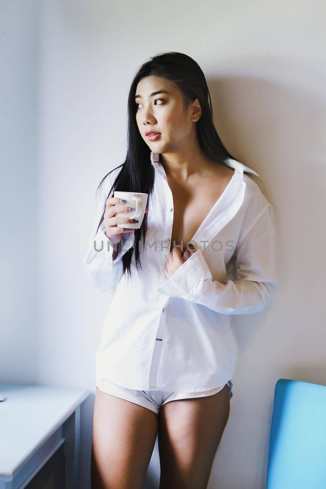 Smiling calm young woman drinking coffee at home