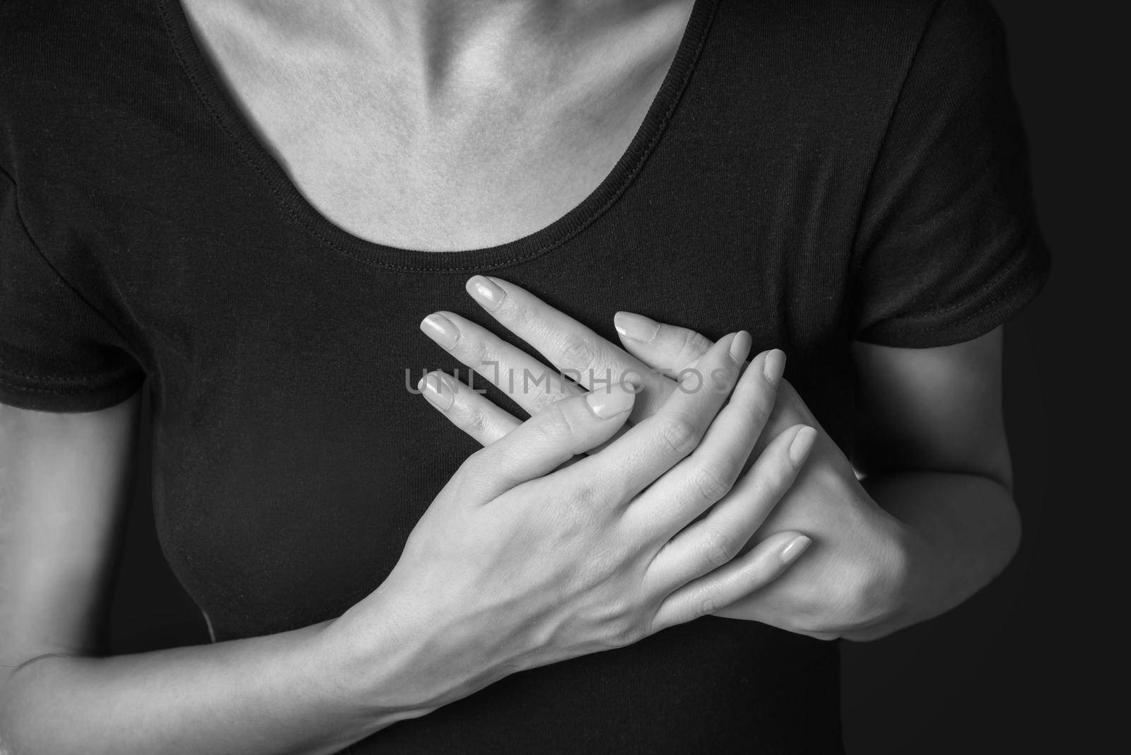 Woman is clutching her chest, acute pain possible heart attack, monochrome image
