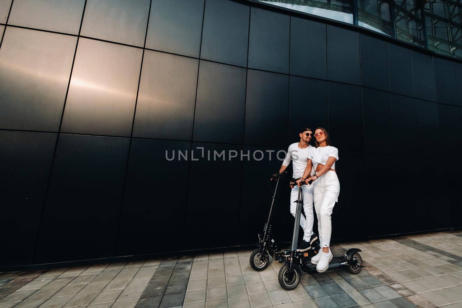 A girl and a guy are walking on electric scooters around the city, a couple in love on scooters