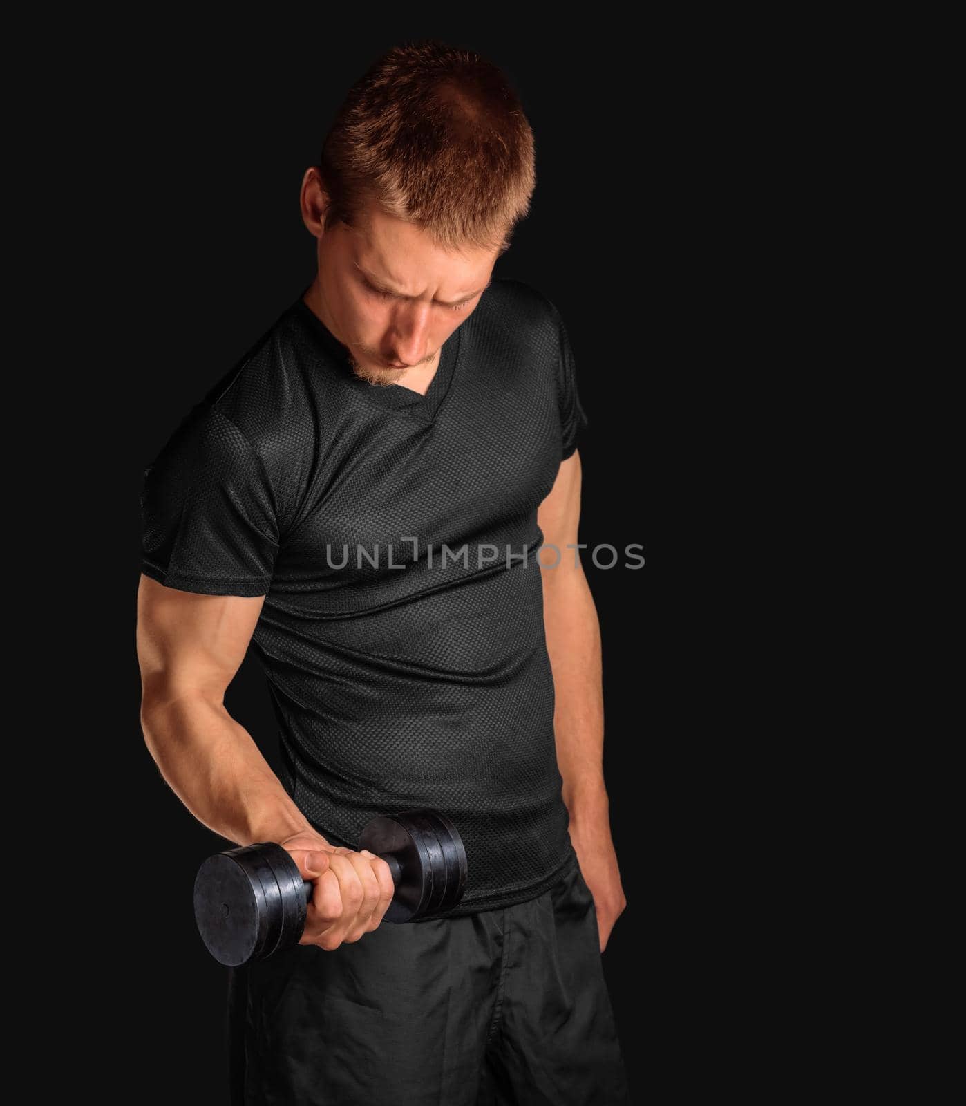 Young man exercises with metal dumbbell