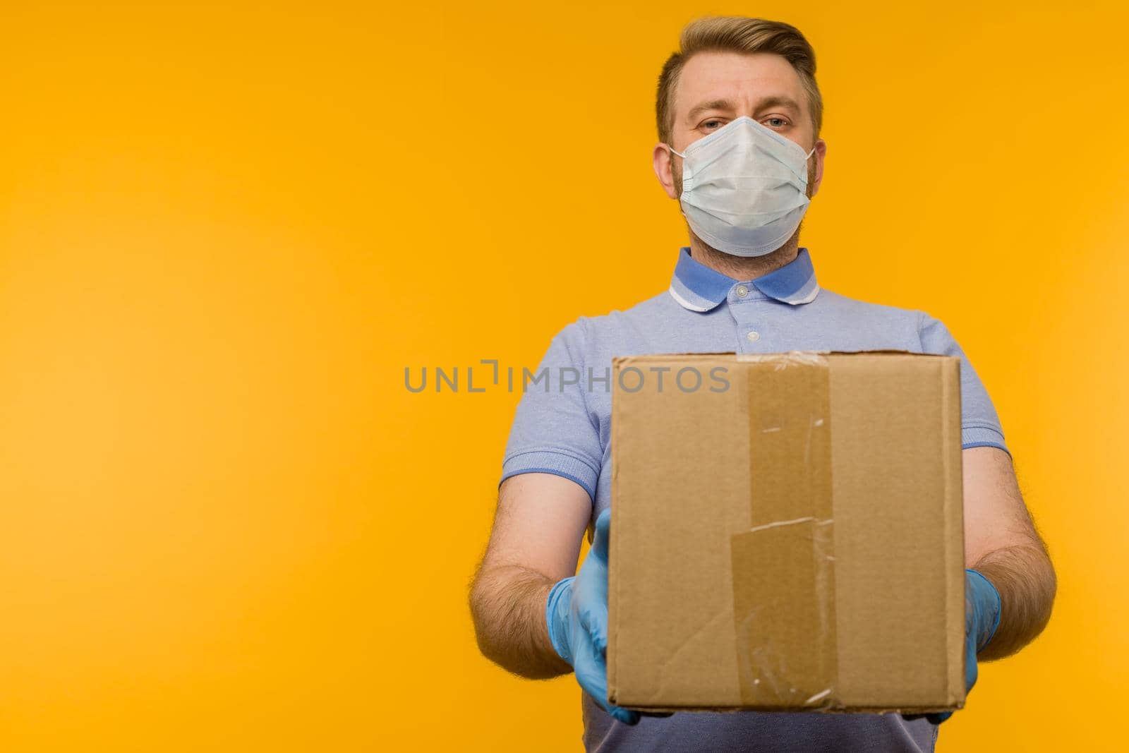 Man holding cardboard boxes in medical rubber gloves and mask. Coronavirus pandemic quarantine delivery concept