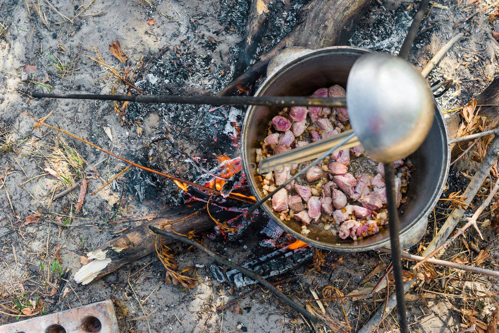 meat stewing in kettle on campfire outside