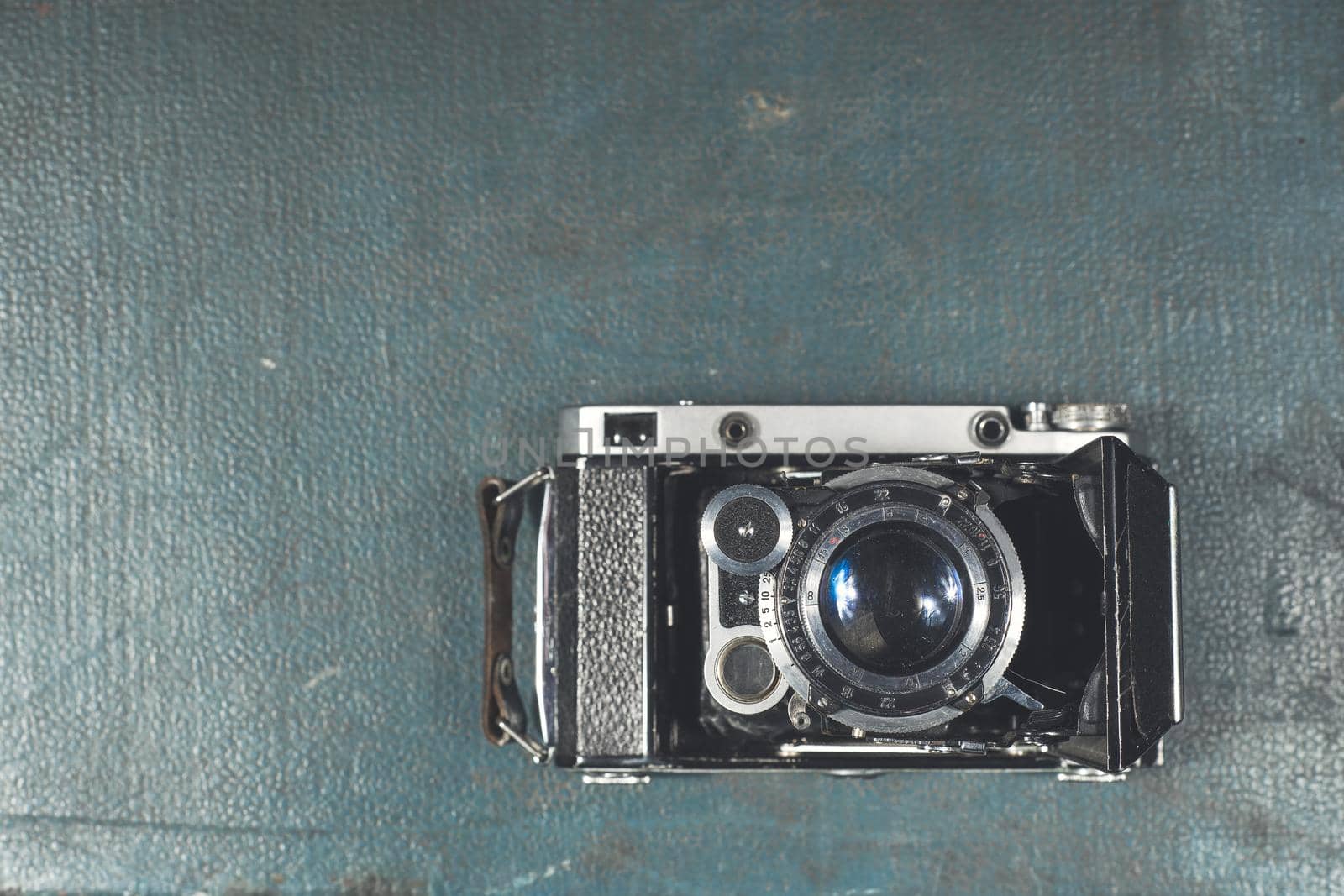 Old vintage camera on a blue scratched background. Focus on the lens.