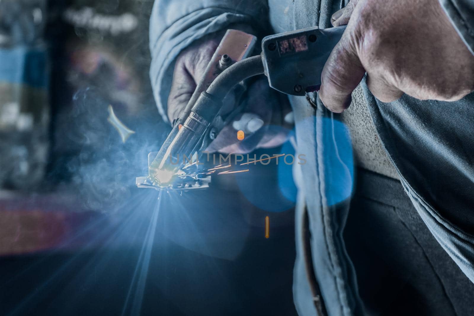 Close-up of the hands of a man welder industrial worker engaged in welding work on metal in the plant by AYDO8