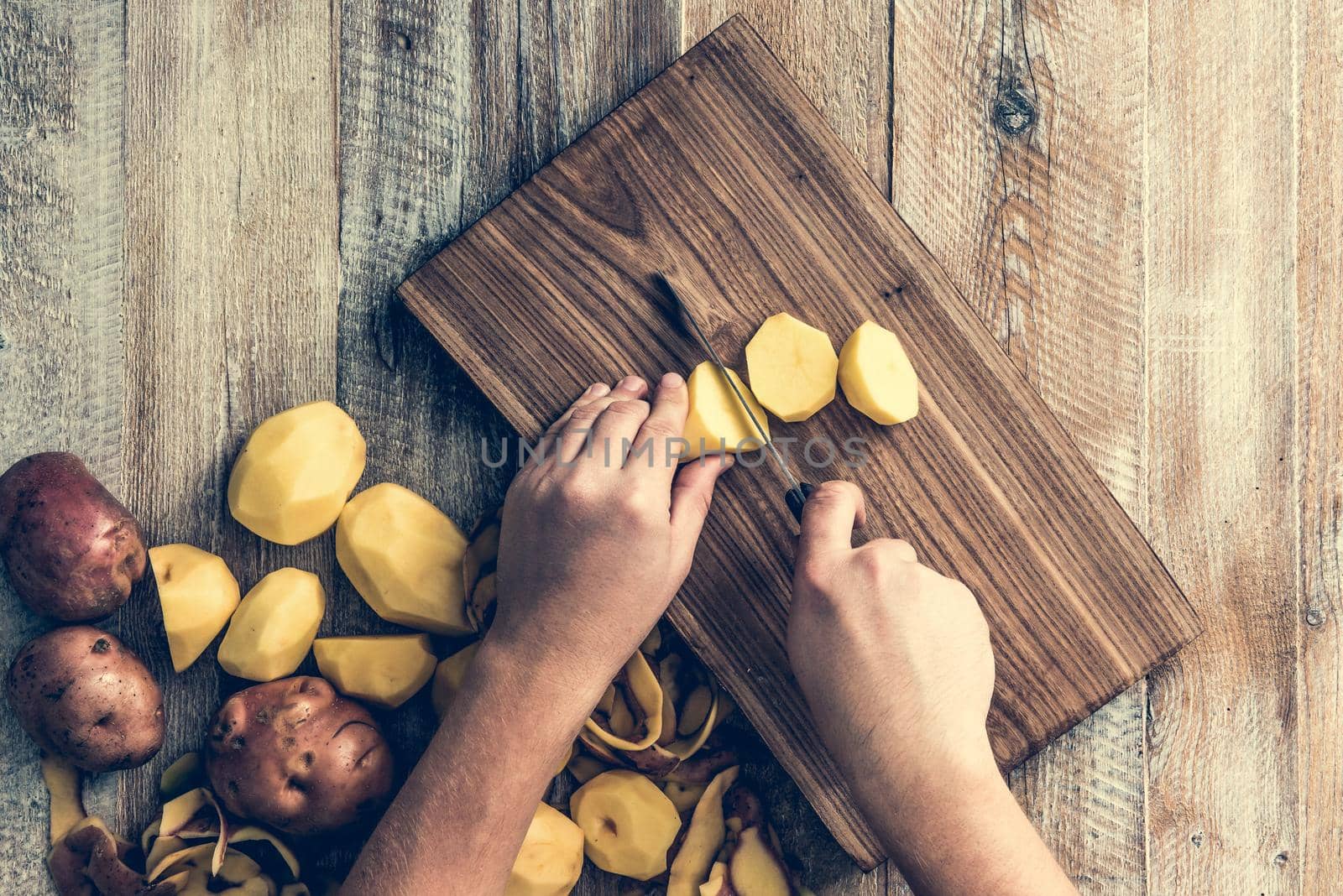 hands cutting potato on wooden board
