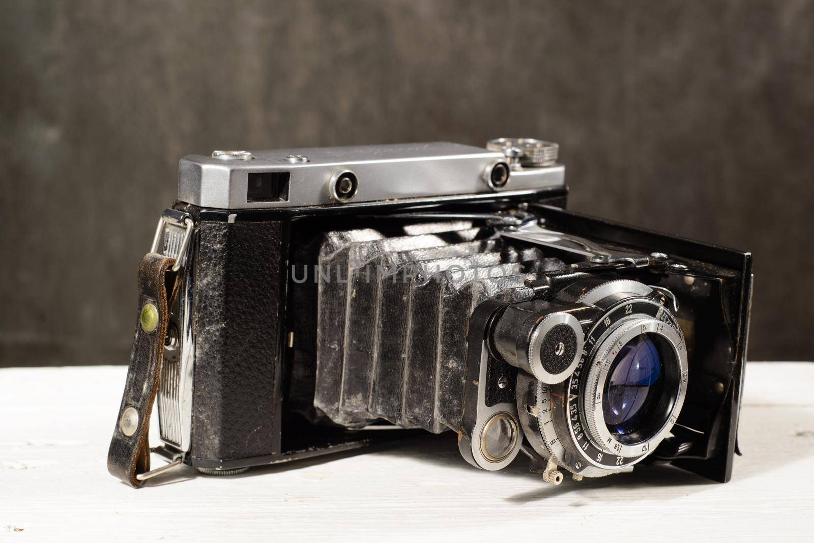 Old vintage camera on white wooden table black background.