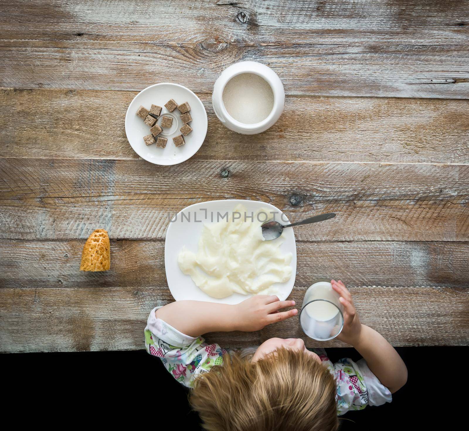 child near table having a meal with semolina