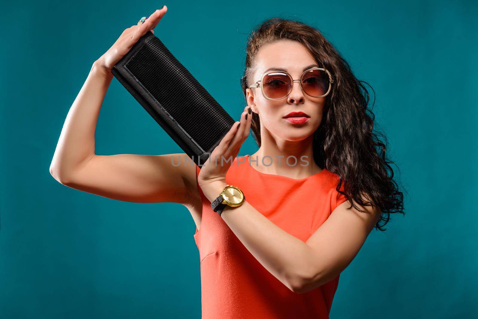 Beautiful girl with a sunglasses and clutch bag in her hands