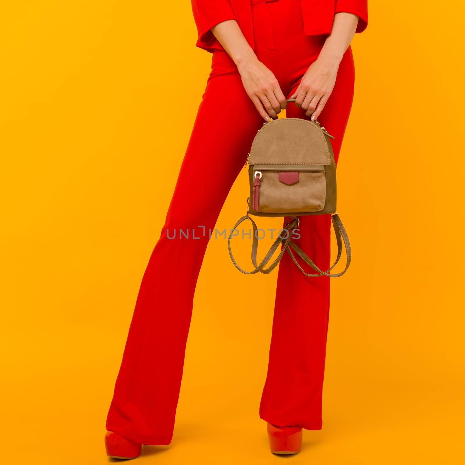 Young girl in a red suit with a small backpack on a yellow background - image