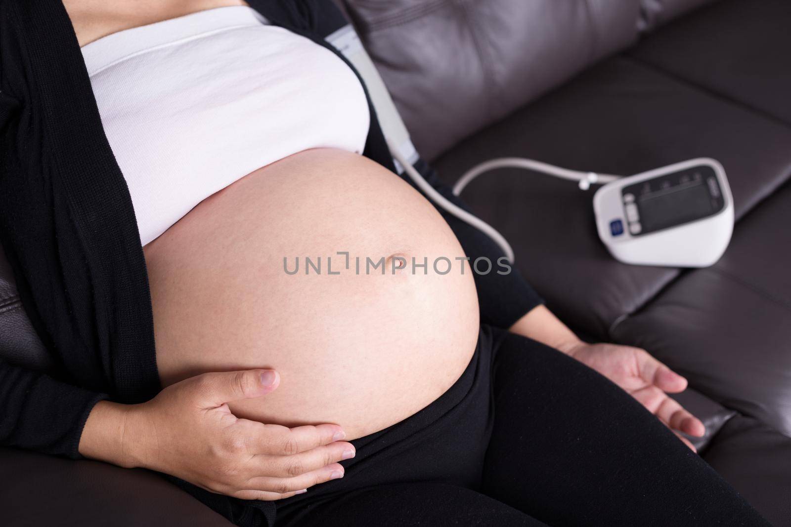 Pregnant woman measures blood pressure with sphygmomanometer