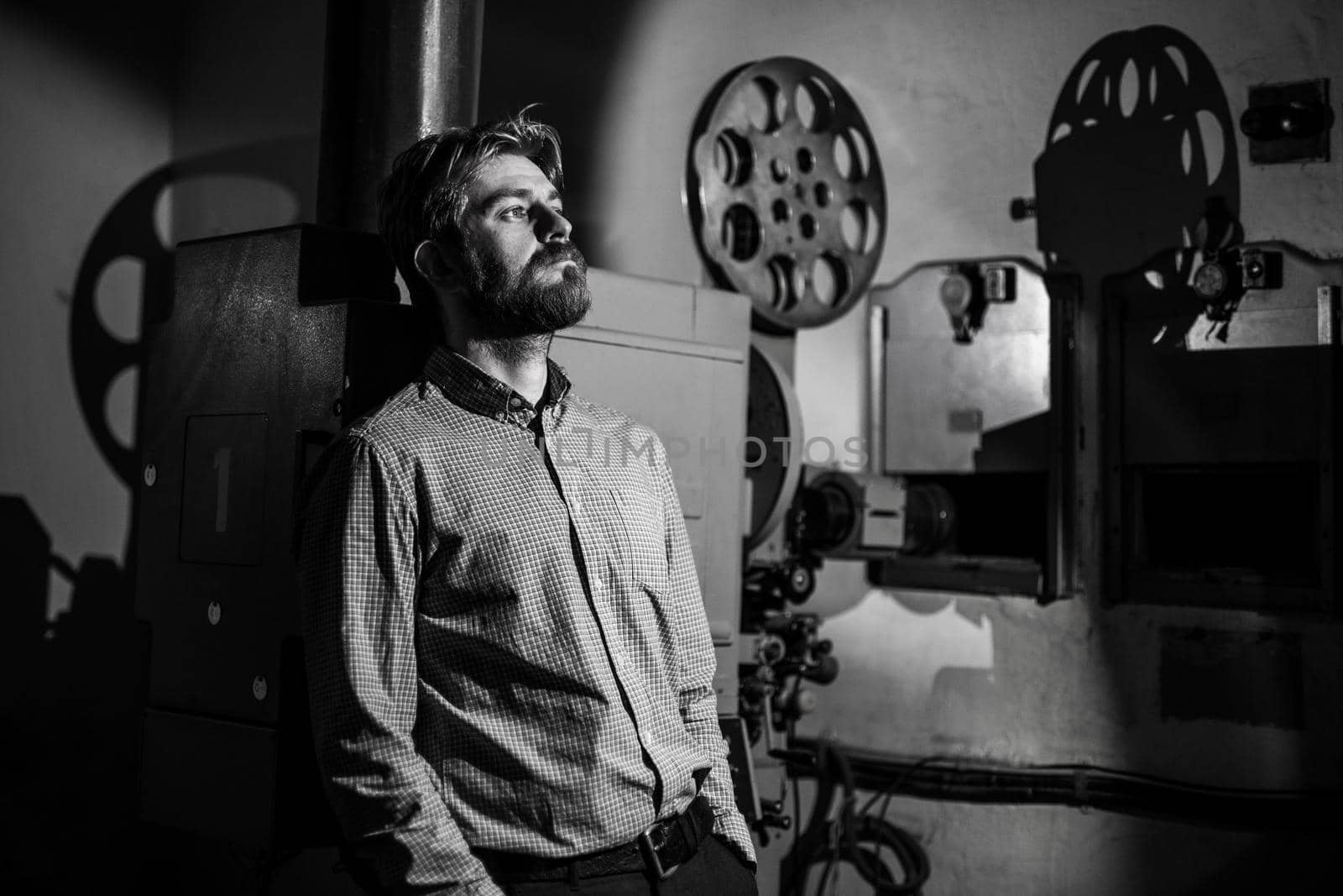 beautiful hipster man standing near a film projector in the room projectionist