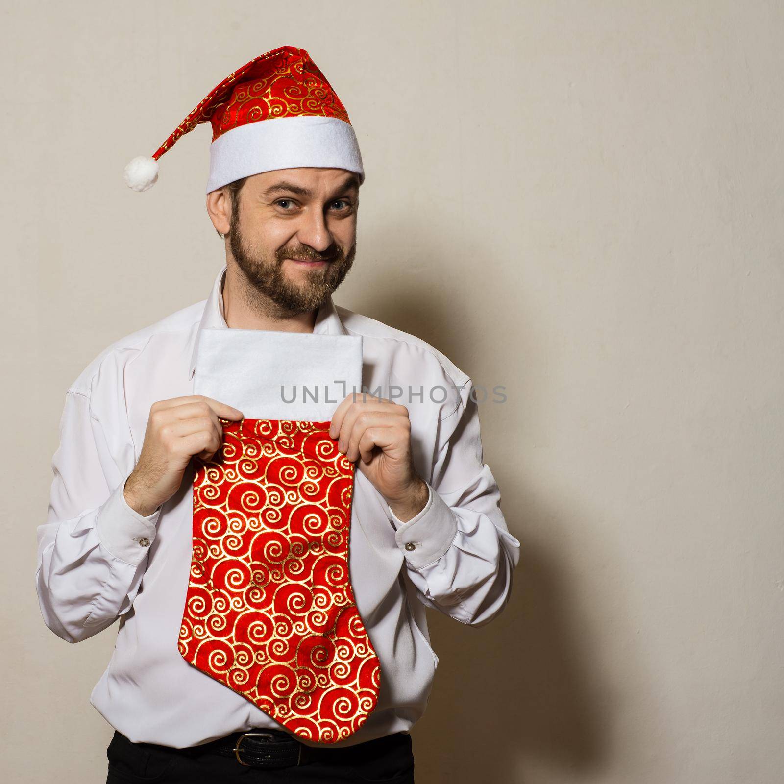 Attractive man in a Christmas cap with a white shirt, socks for gifts in hands