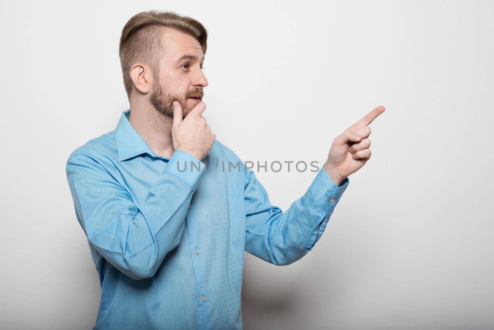 handsome man with beard pointing in one direction on a white background