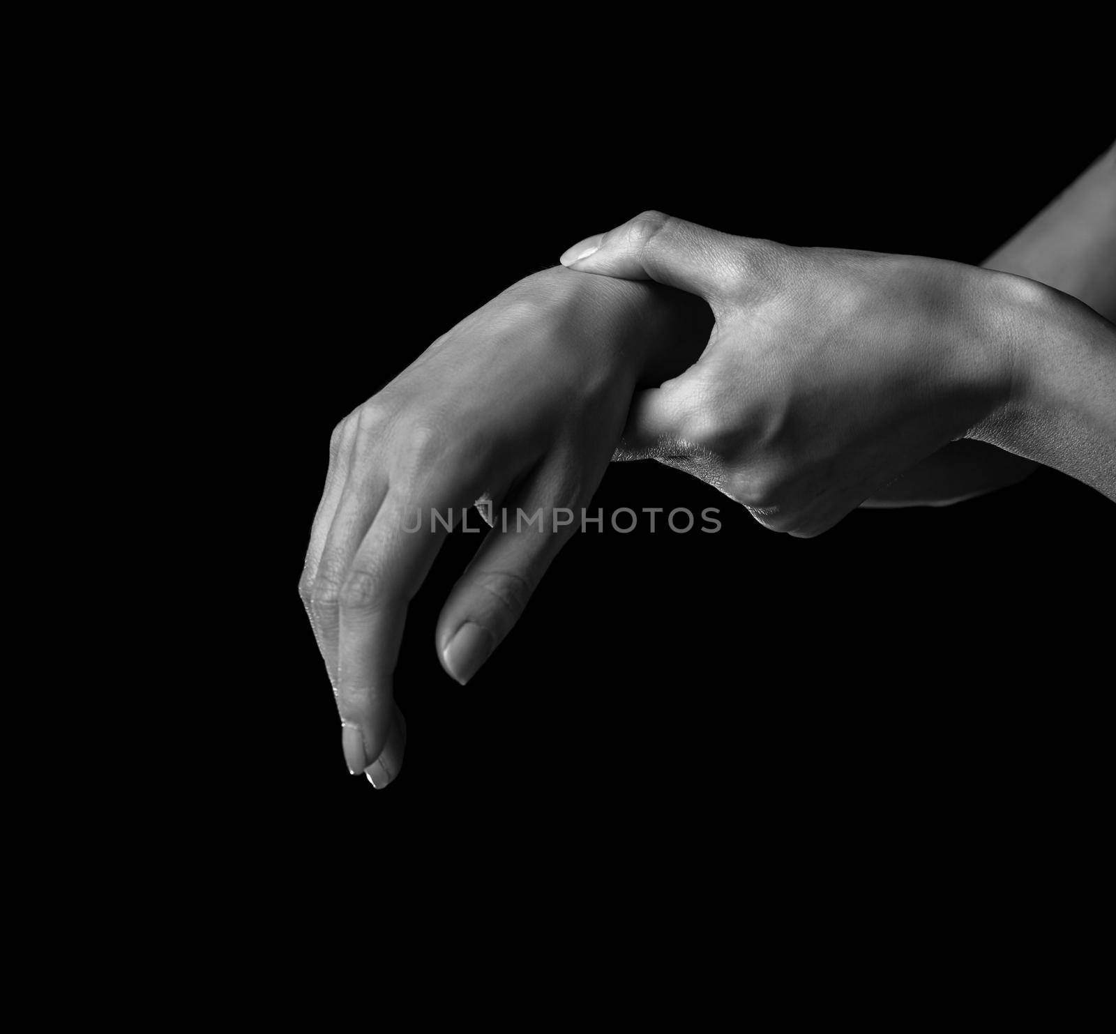 Pain in a female wrist. Woman holds her hand, monochrome image