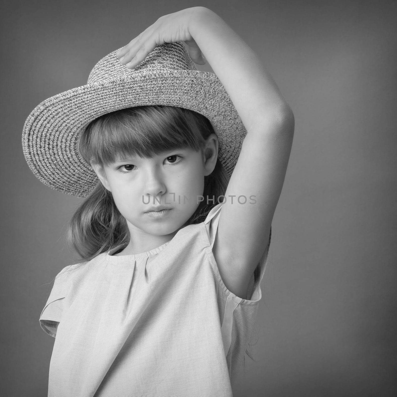 Close up portrait of cute girl in straw hat. Black and white shot of preteen child posing half turned to the camera. Lovely girl looking seriously at camera