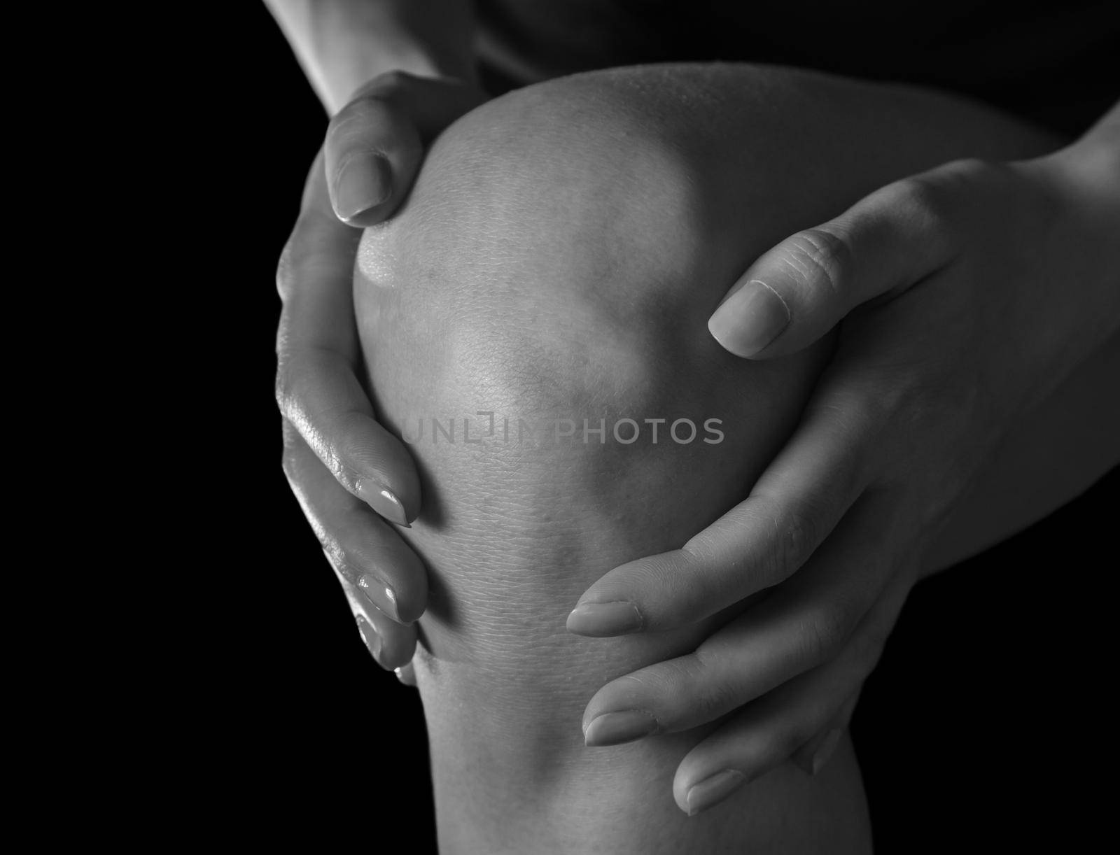 Woman holds her knee, pain in the knee joint, monochrome image