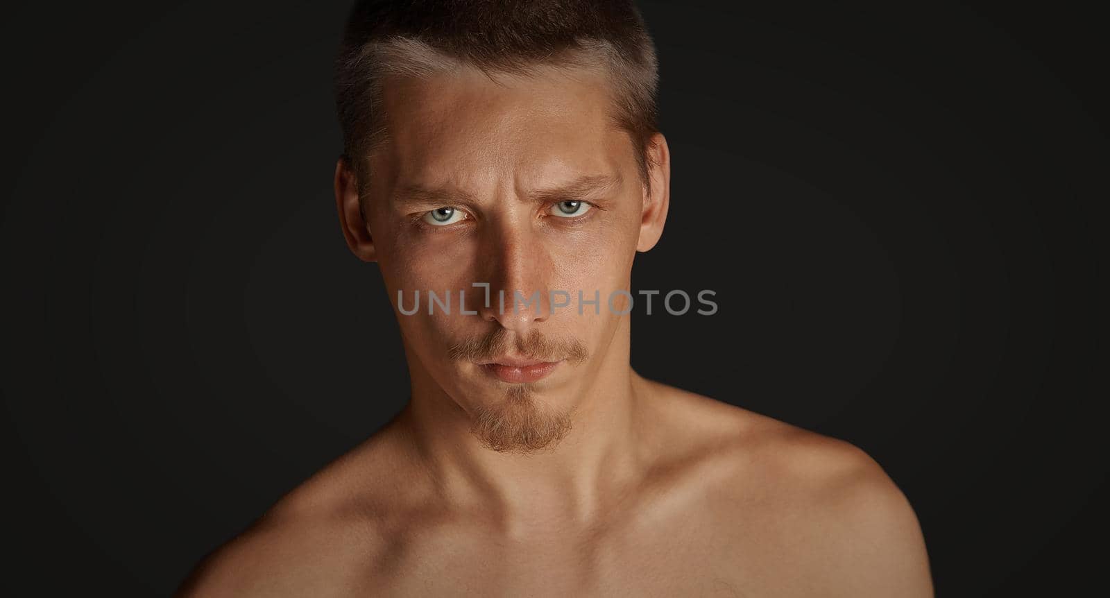 Portrait of young serious man on black background