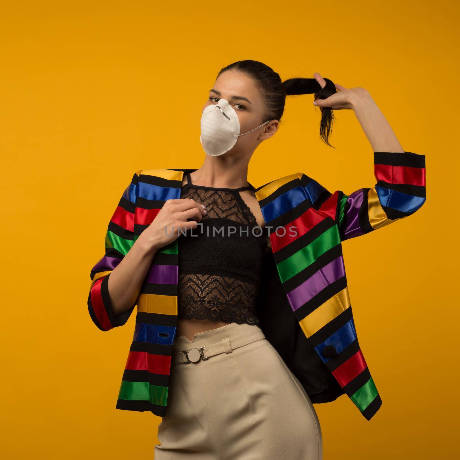 Beautiful slim girl fashion model posing in a protective respirator on a yellow background. by zartarn