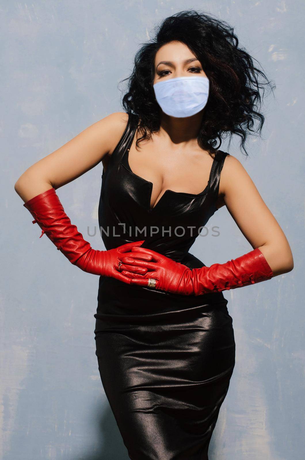 Beautiful adult woman wearing in protection mask black spandex dress and long red leather gloves - image