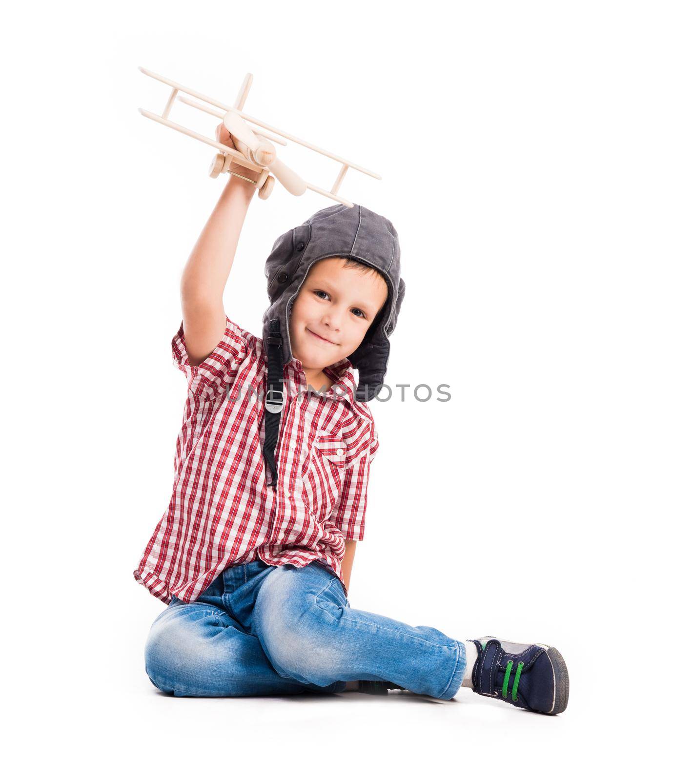 little boy with pilot hat and toy airplane sitting isolated on white background