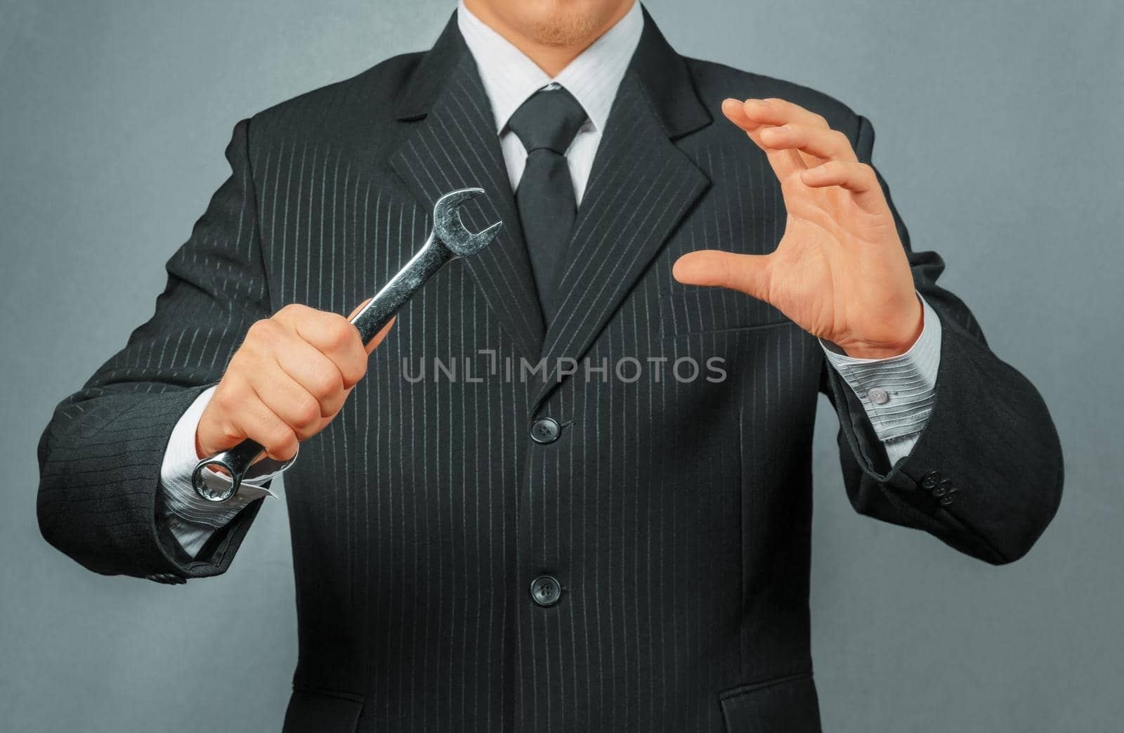 Unrecognizable businessman holds metal wrench, focus on wrench, concept of business creation