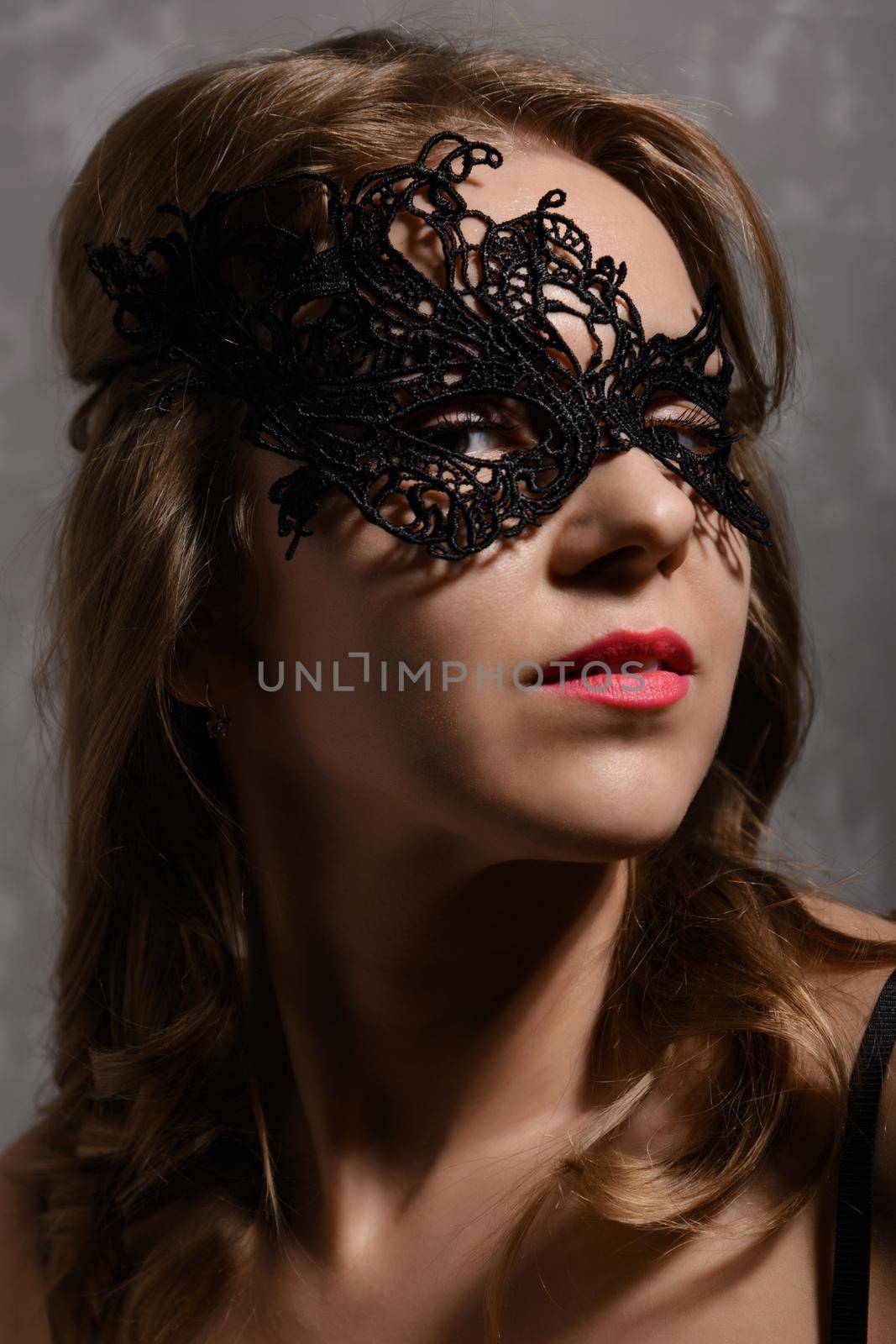 Close-up portrait of young sensual ginger woman wearing black party mask