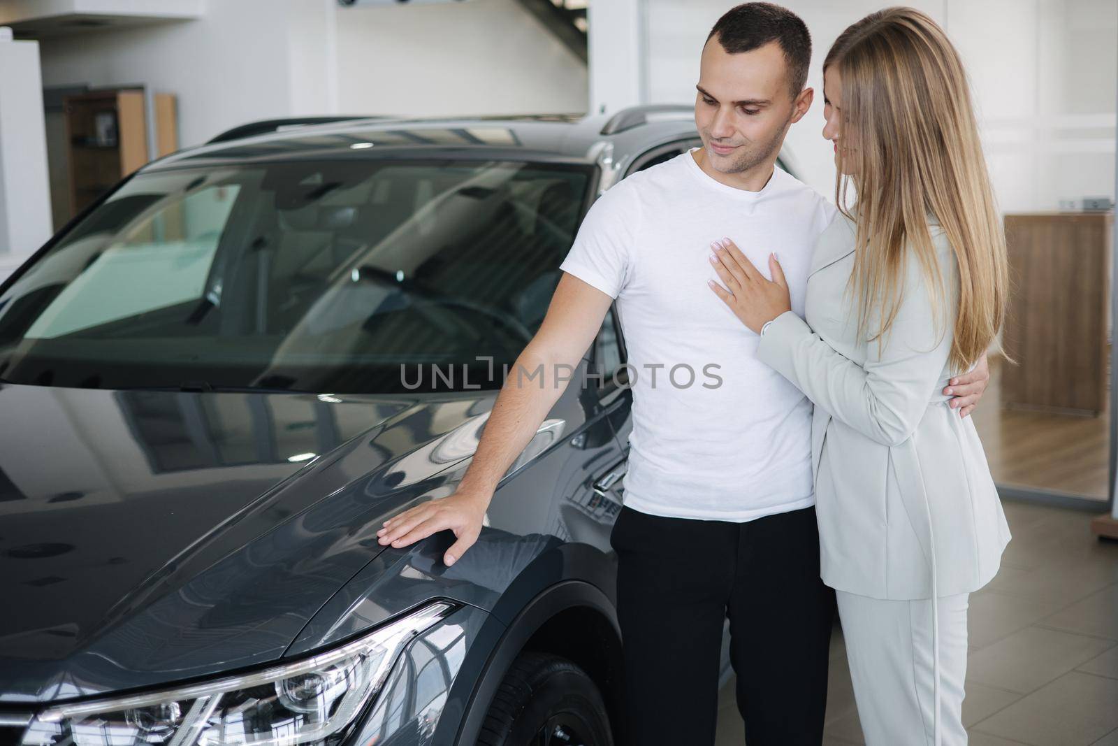 Portrait of beautiful young couple happy after buying new car from car showroom. Woman hus her man and glad.