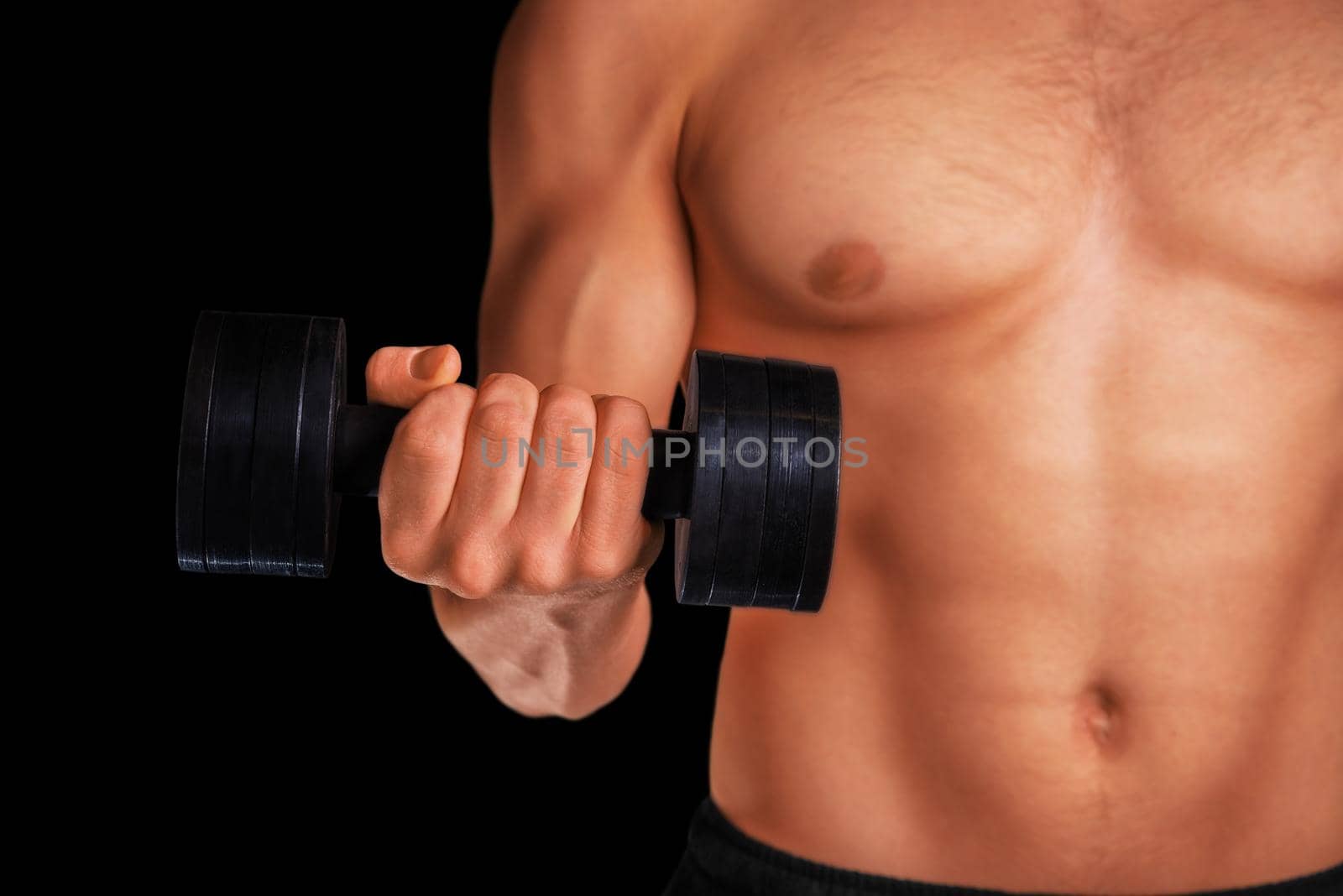Muscular sportsman exercises with metal dumbbell