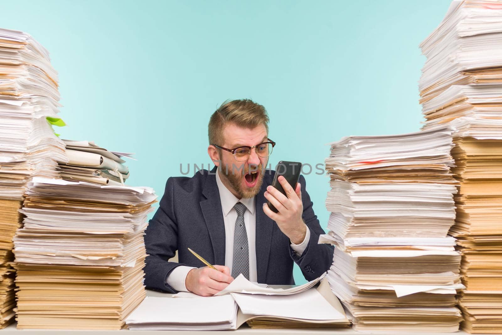 Business executive swears on the phone for poorly done work working in the office and piles of paperwork, he is overloaded with work - image