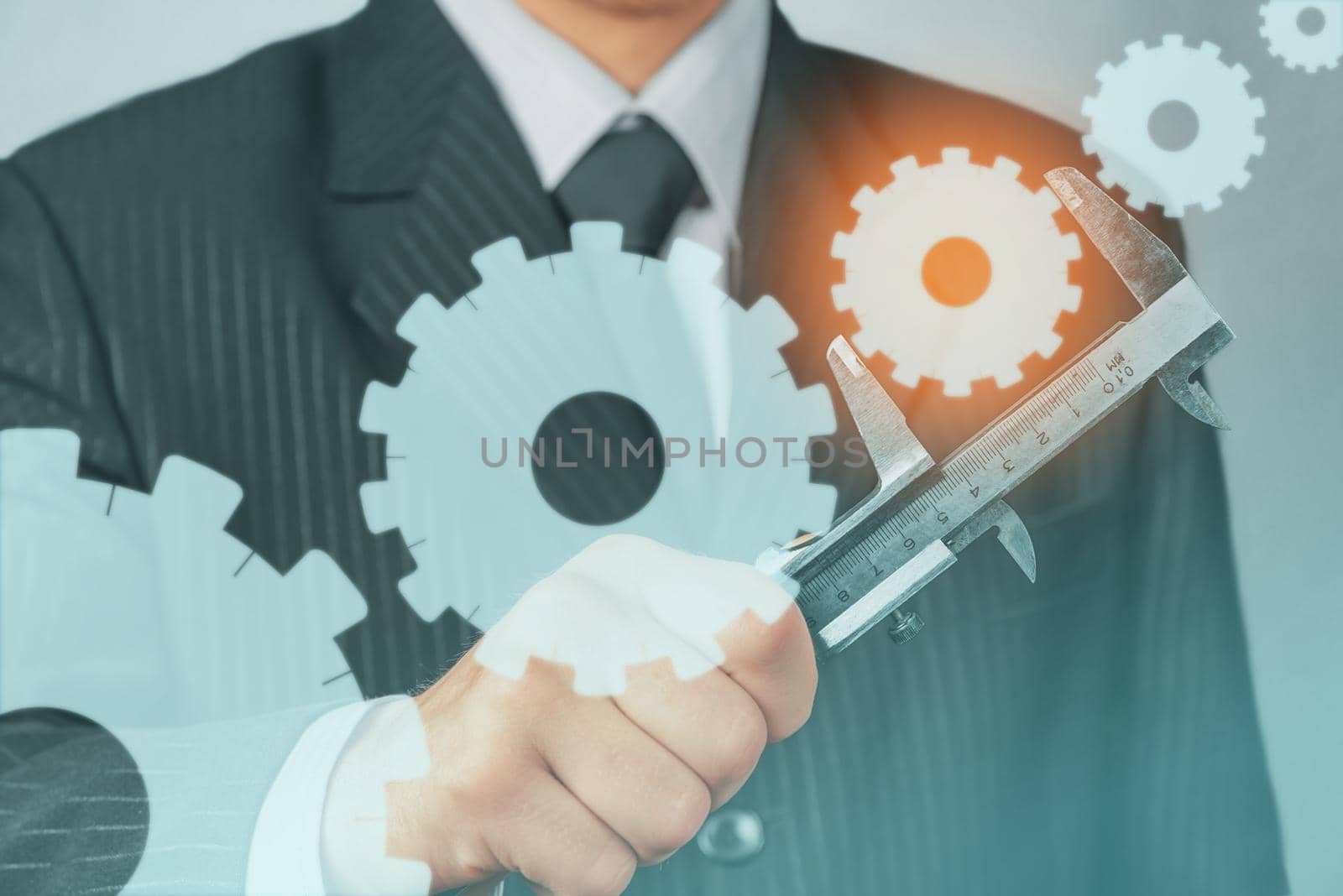 Unrecognizable businessman holds metal calipers with cogwheels, concept of business creation