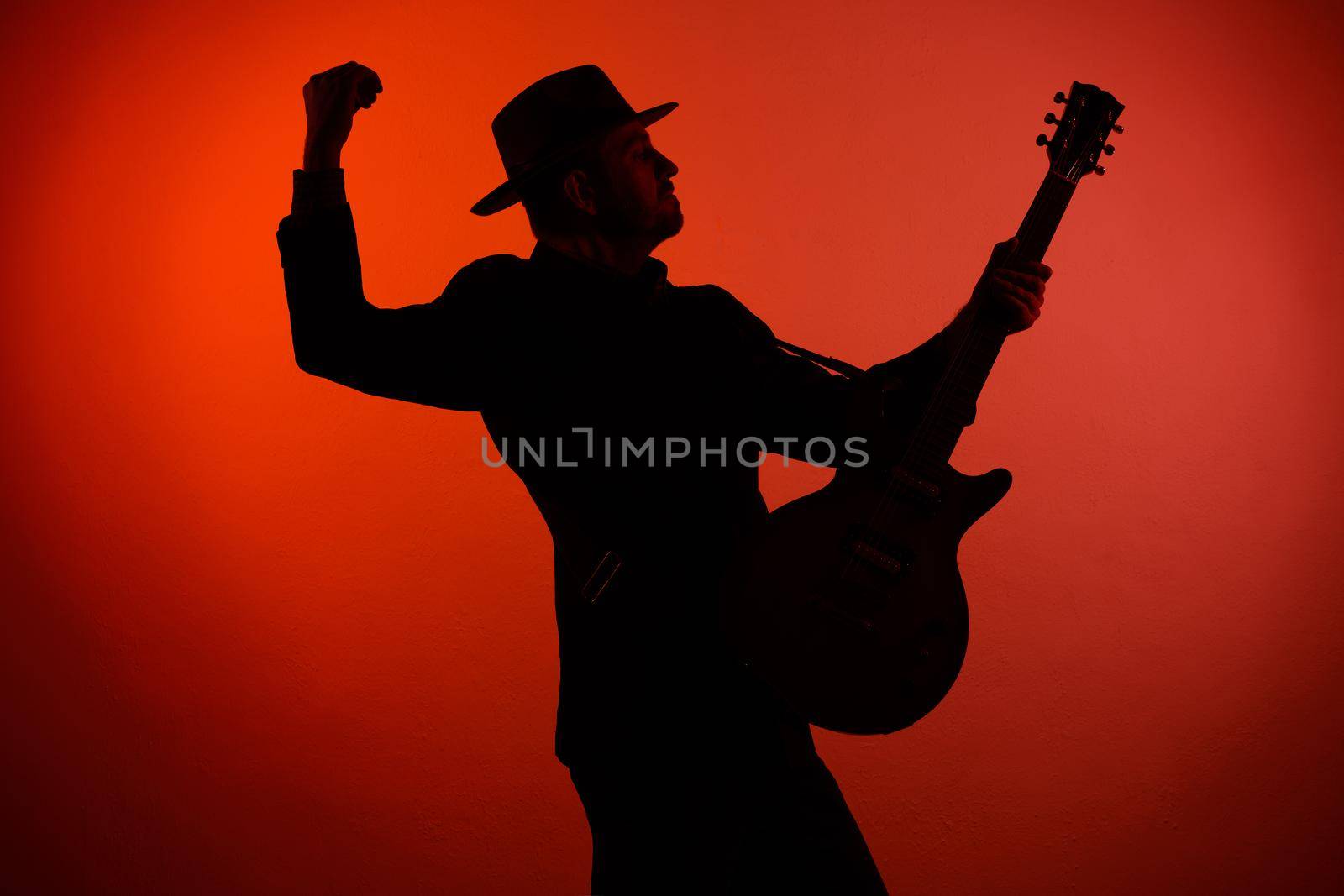 silhouette of a musician playing instrument in a hat on a red background