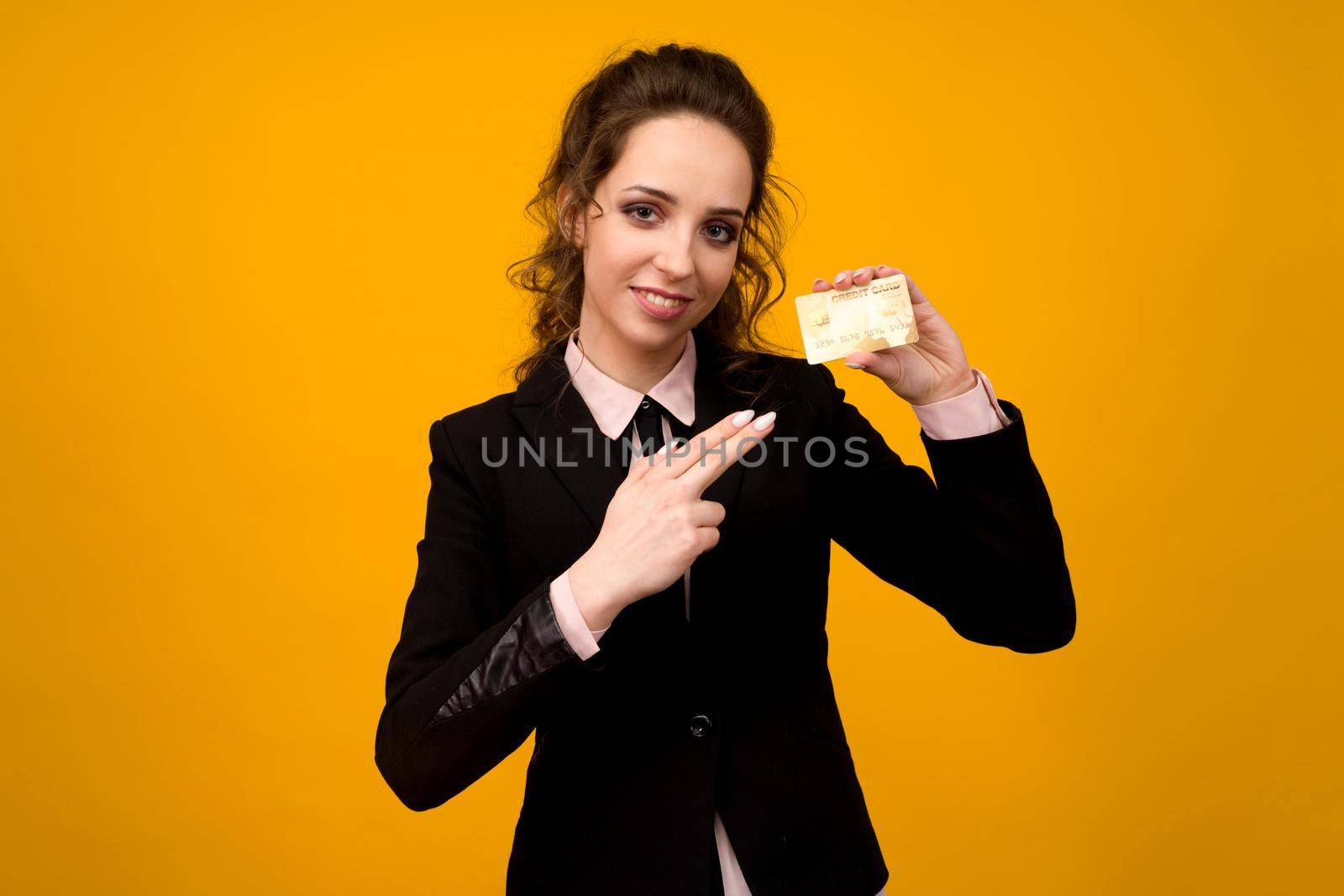 Portrait of a beautiful young business woman standing isolated over yellow background, holding credit card - image