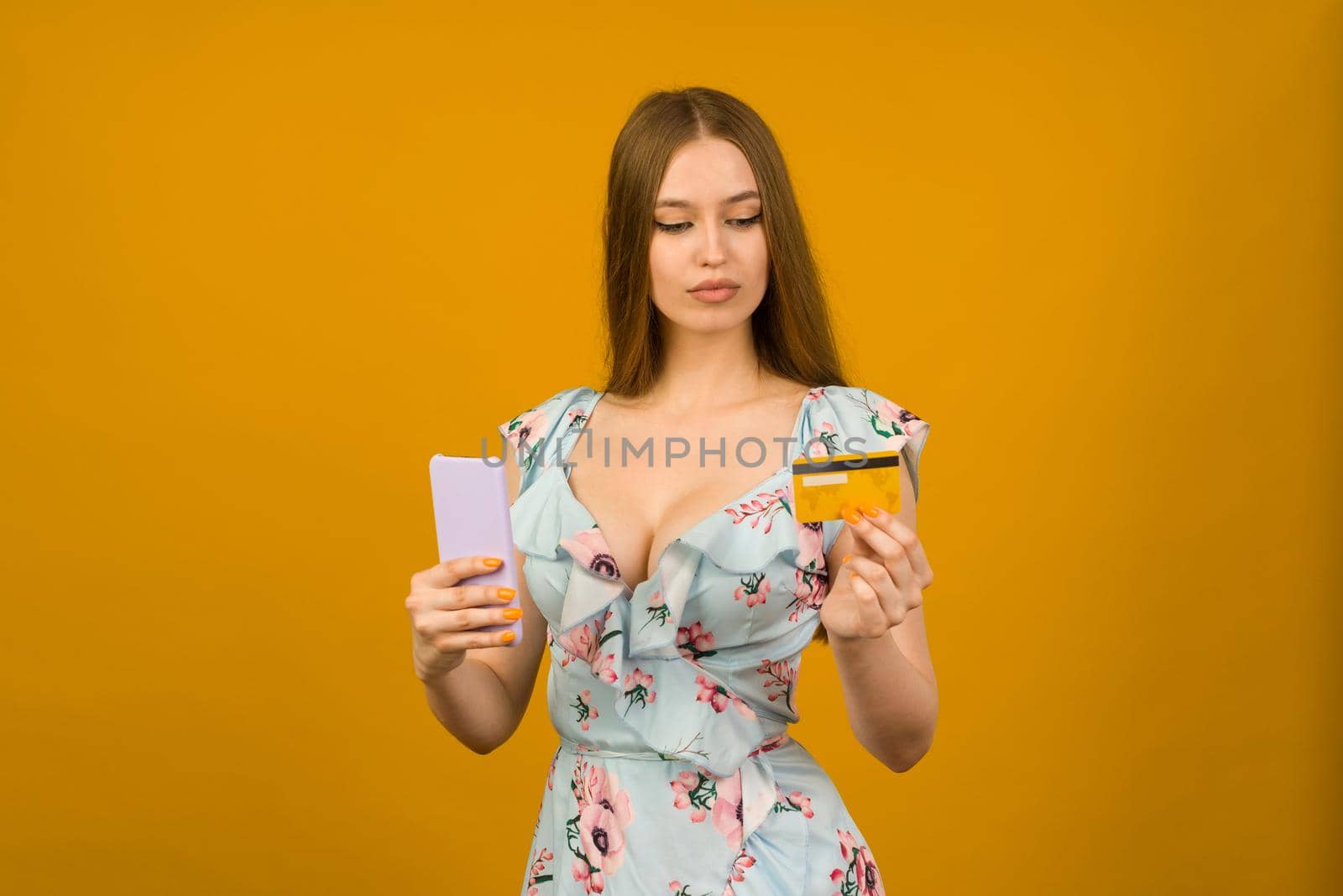 Lady buying online with a credit card and smart phone on yellow background - image