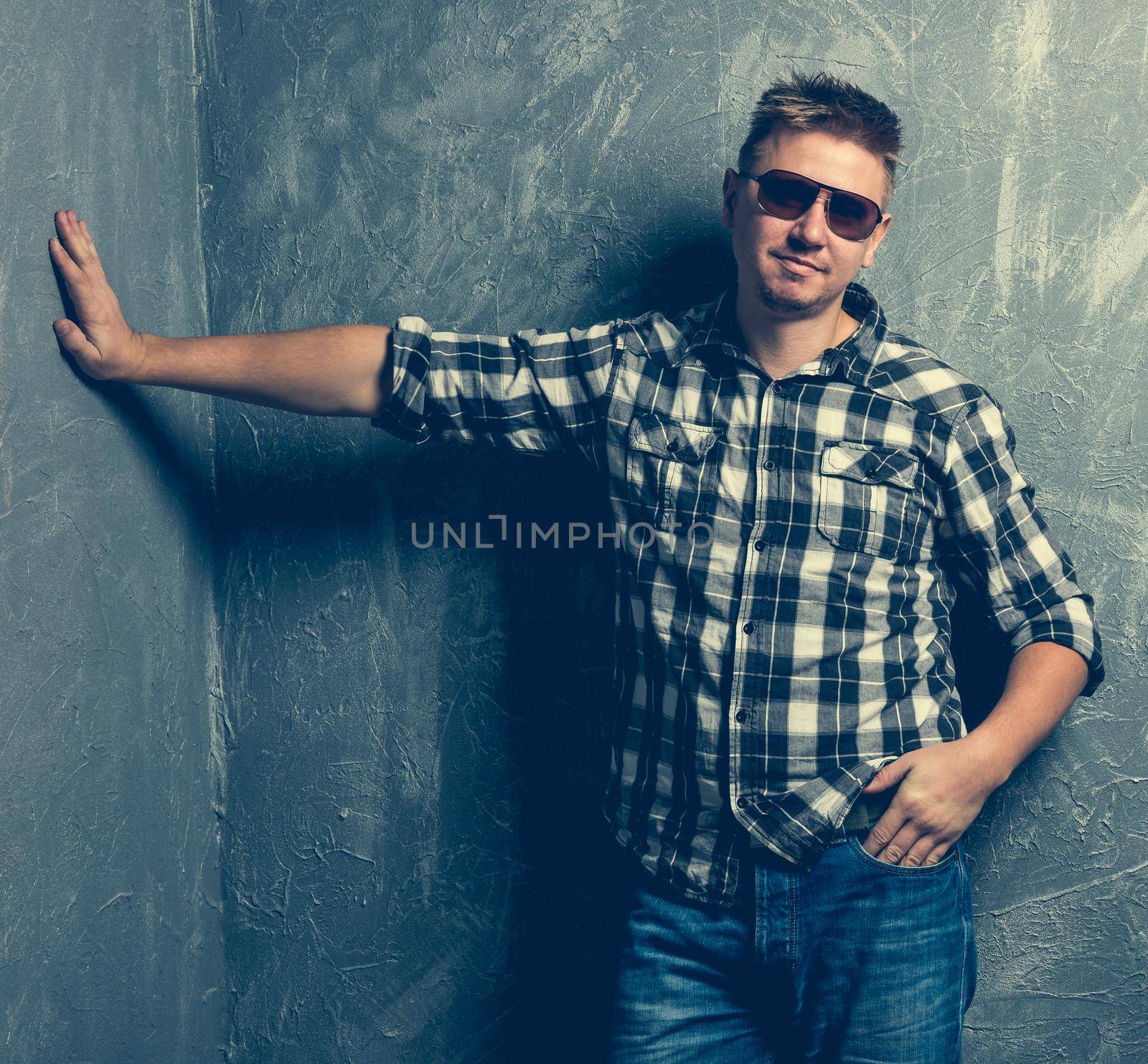 man with his hand rest against the wall on grey background