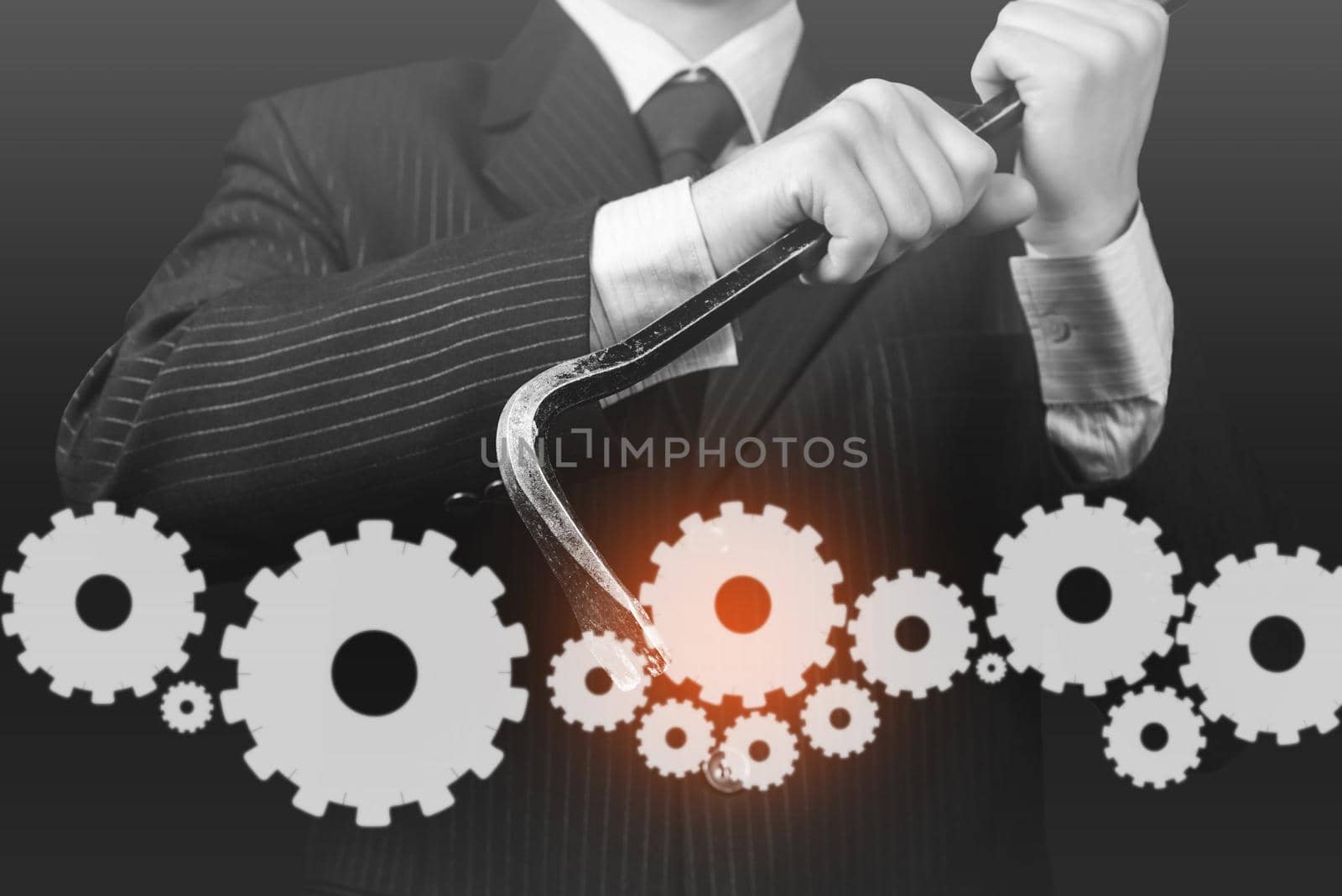 usinessman in a suit holds metal crowbar with cogwheels, concept of business creation, monochrome image