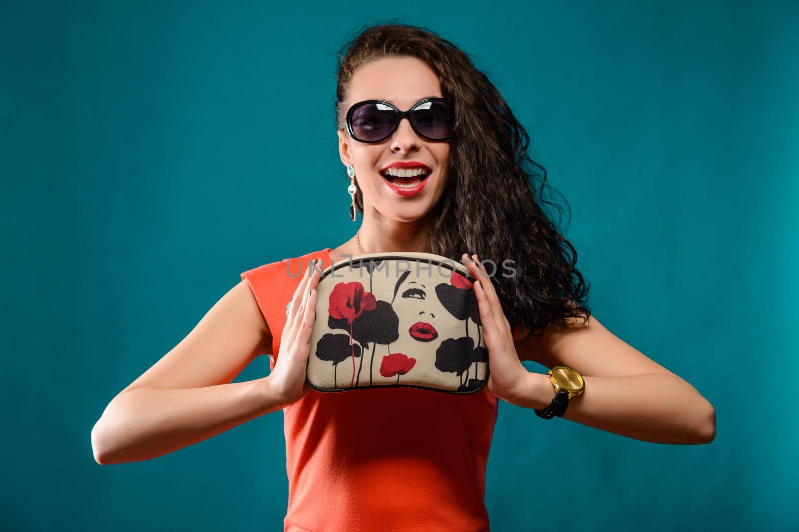 Beautiful girl with a sunglasses and clutch bag in her hands.