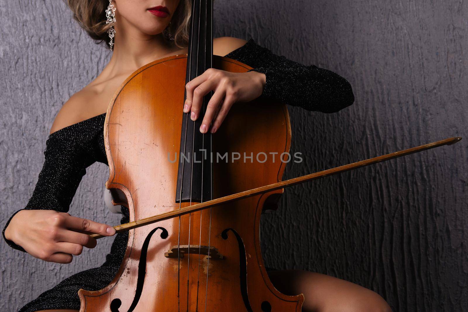 female hands with a bow on cello strings.