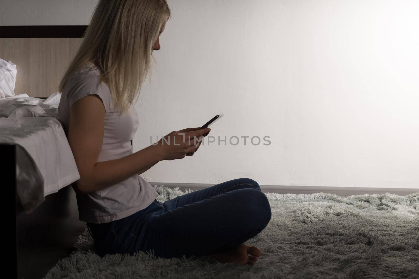 teenager girls sitting on the floor near bad typing on the mobile phone. Young woman suffers from insomnia