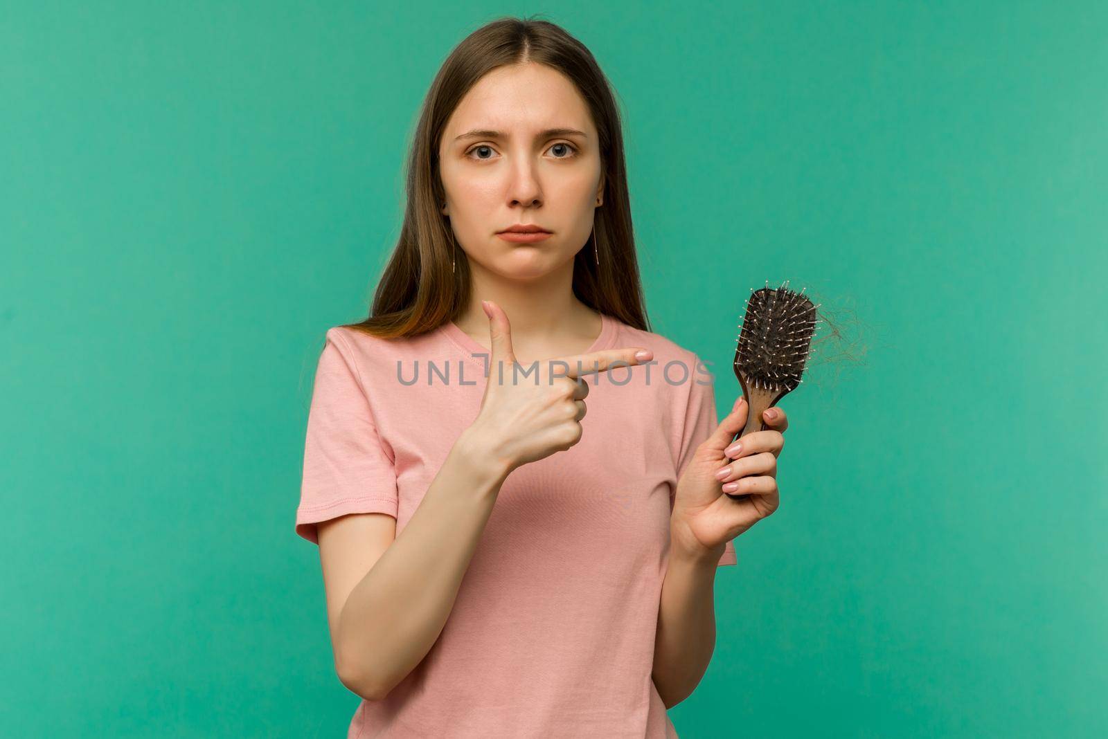 Young girl with a comb and problem hair on blue background - image