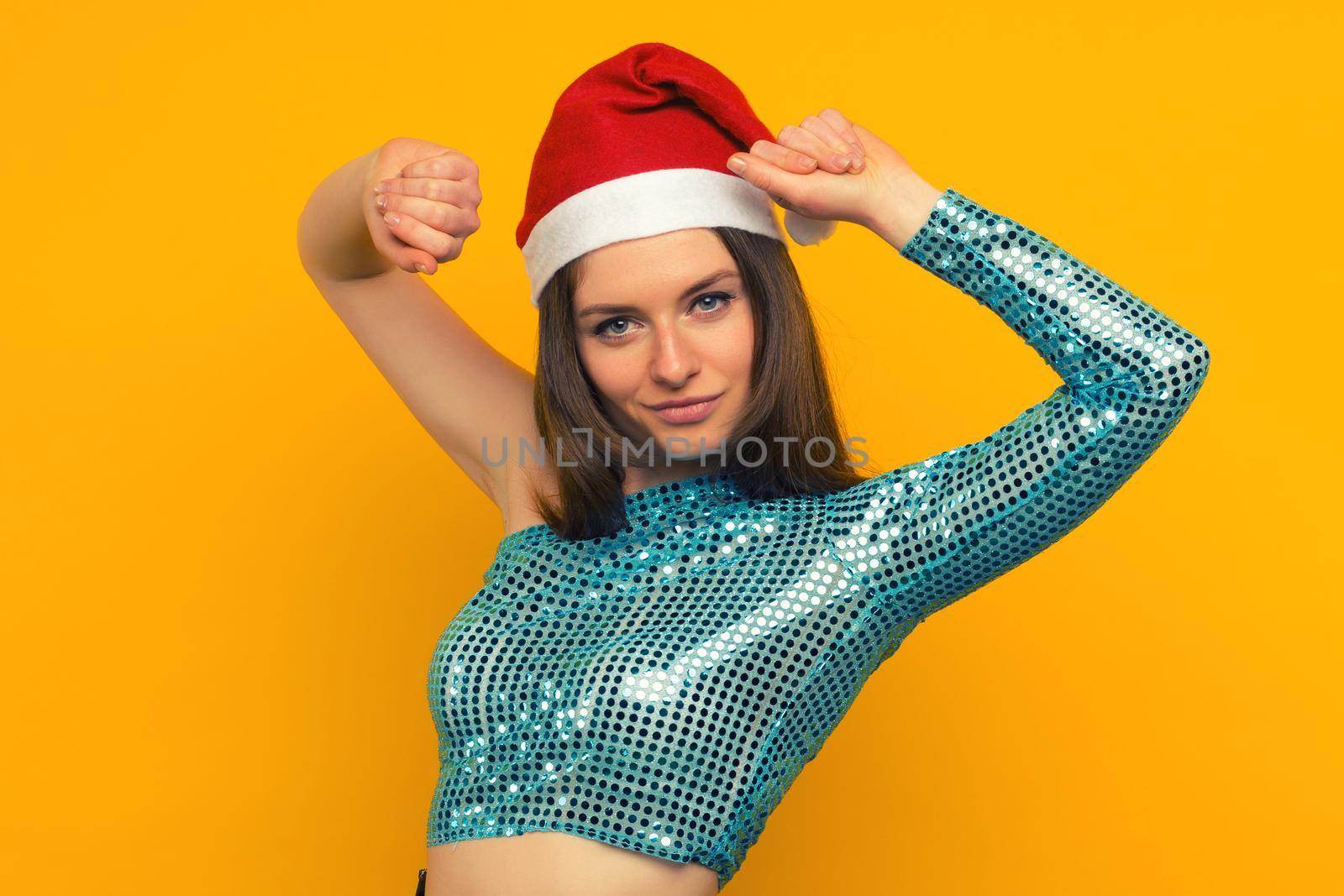 Joyful girl dancing in a Christmas hat on a yellow background - image