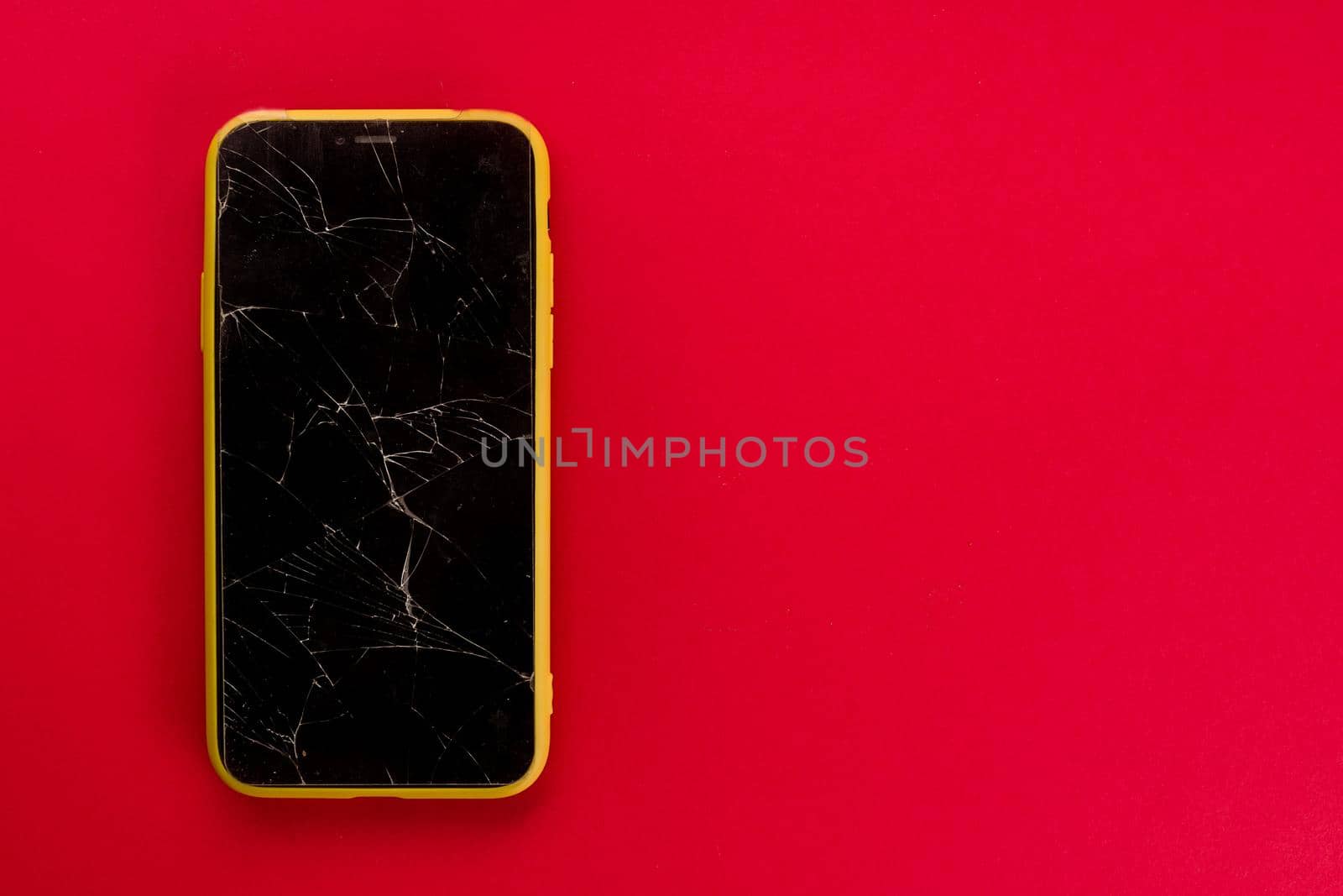 Smartphone with broken screen on red background - image