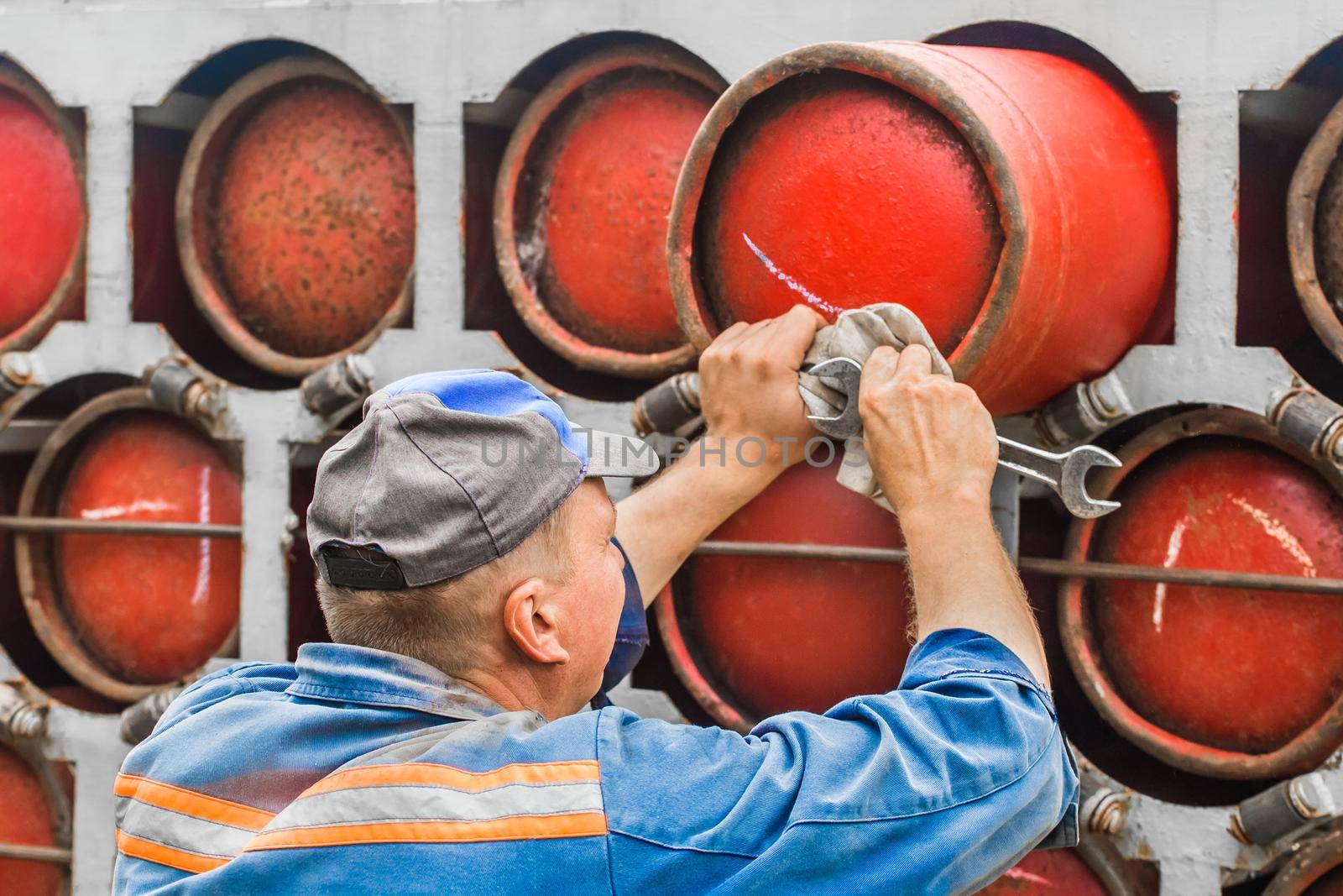 Adult male worker pushing a gas cylinder into a gas machine.