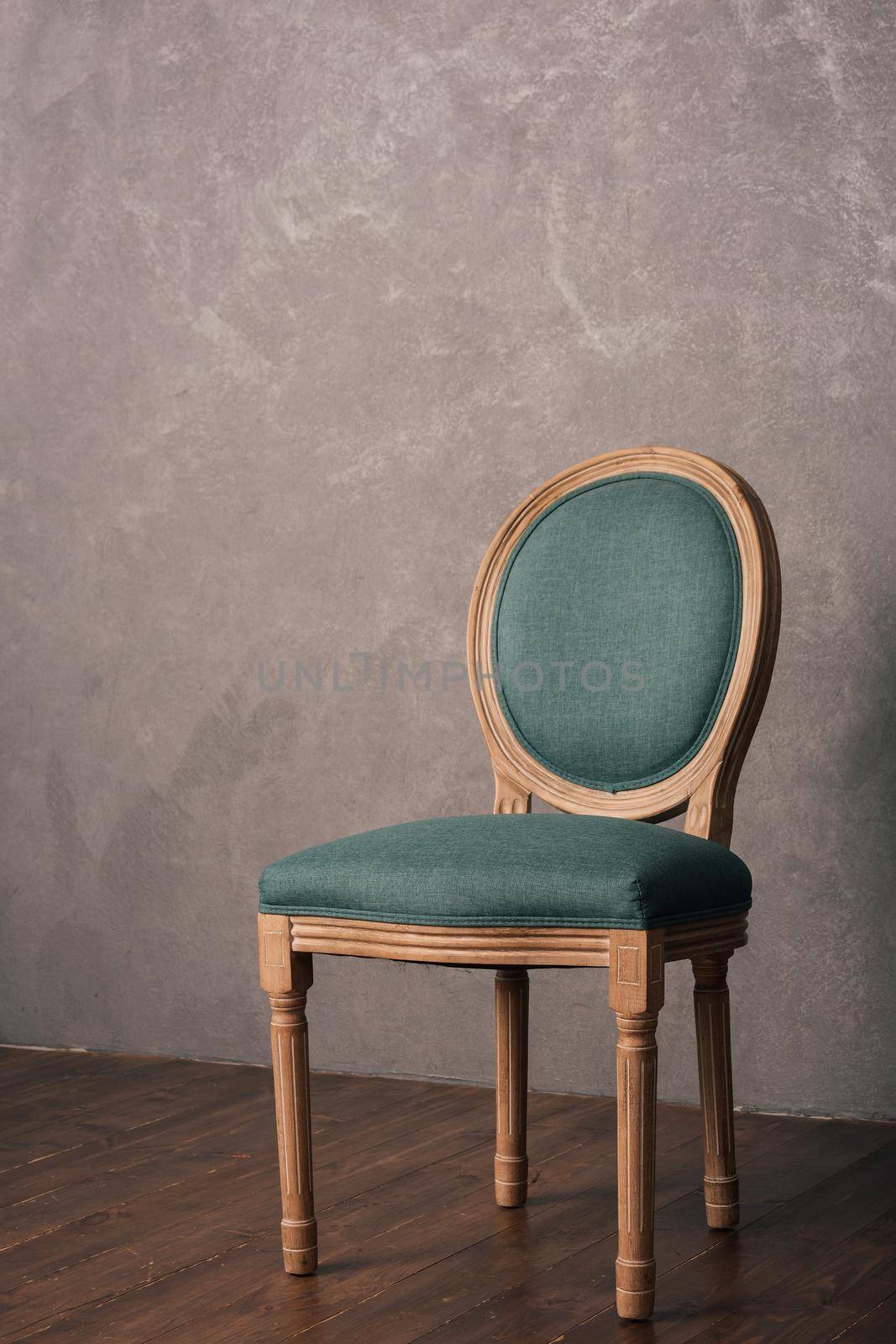 Green luxurious vintage chair stands on a dark wooden floor by zartarn