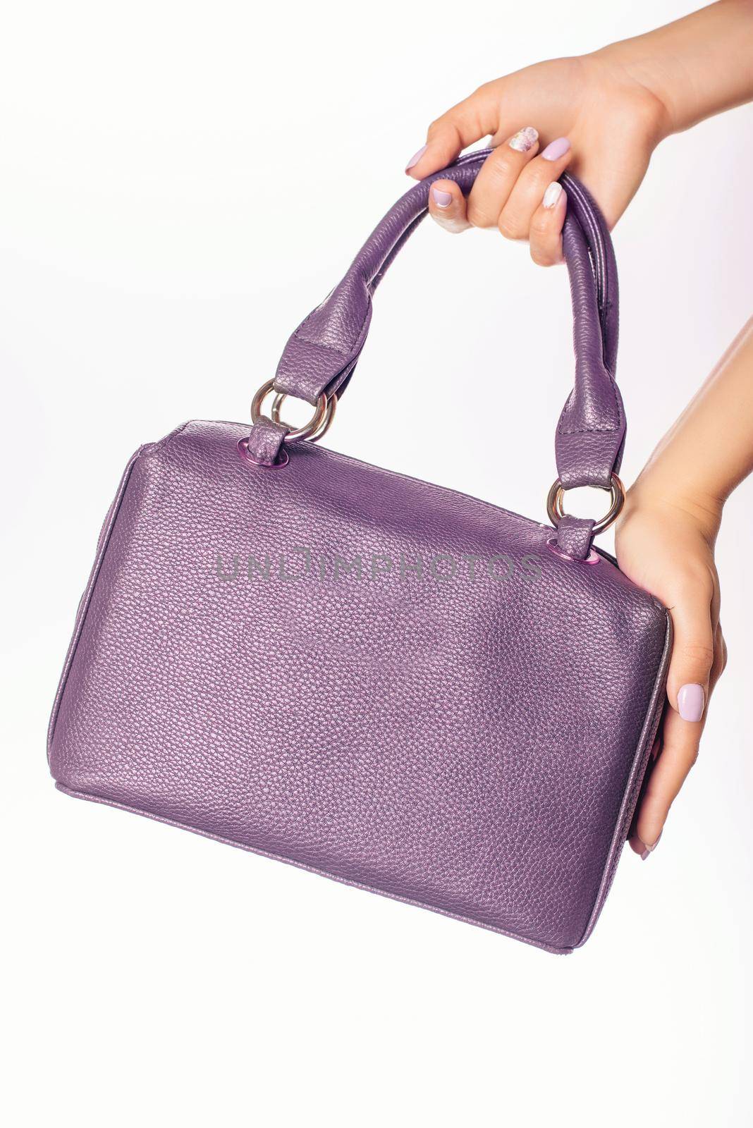 Close up photo of trendy violet bag in hands of fashionable woman . Fashion elements